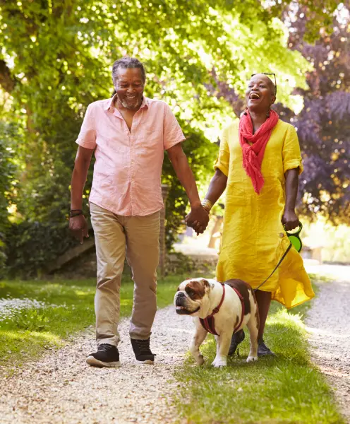 old couple walking dog and smiling for some reson